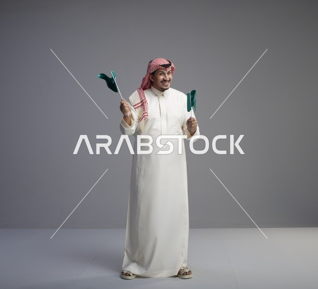 رجل سعودي يحمل الأعلام السعودية في احتفال وطني