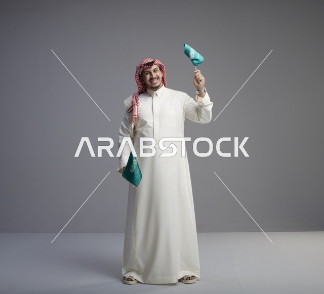 رجل سعودي يحمل الأعلام الوطنية السعودية في استوديو احترافي