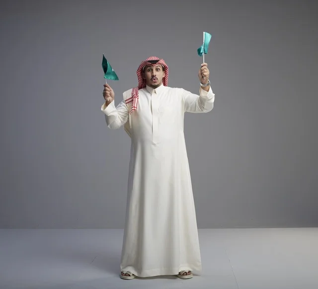 Saudi Man Holding National Flags Against Gray Background - Photo