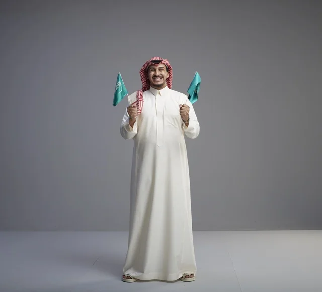 رجل سعودي يحمل الأعلام الوطنية في استوديو