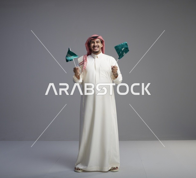 رجل سعودي يحمل الأعلام الوطنية السعودية في استوديو