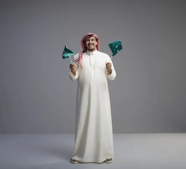 رجل سعودي يحمل الأعلام الوطنية السعودية في استوديو