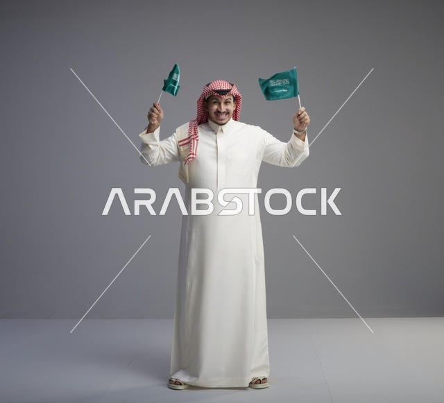رجل سعودي يحمل الأعلام الوطنية في استوديو تصوير
