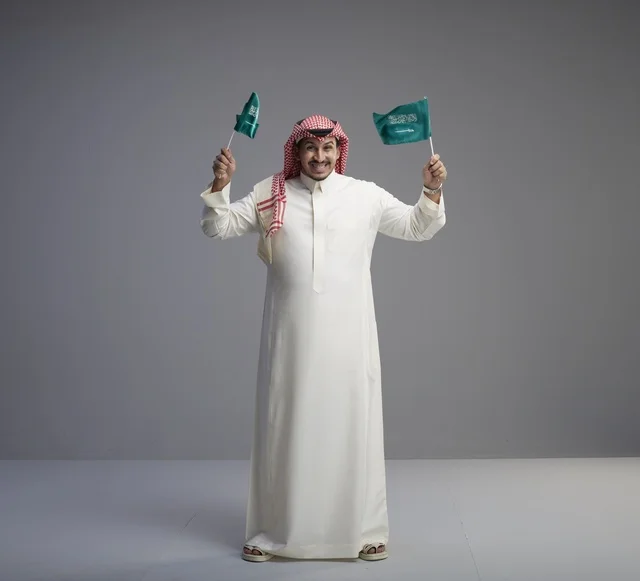 رجل سعودي يحمل الأعلام الوطنية في استوديو تصوير