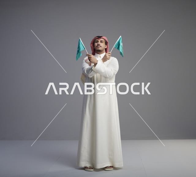 رجل سعودي يحمل أعلام المملكة العربية السعودية في استوديو