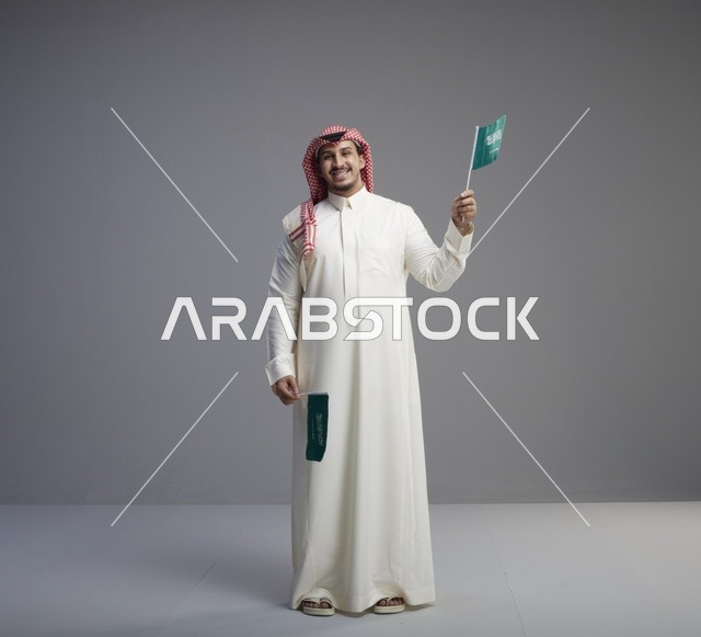 رجل سعودي يحمل الأعلام الوطنية في الاستوديو