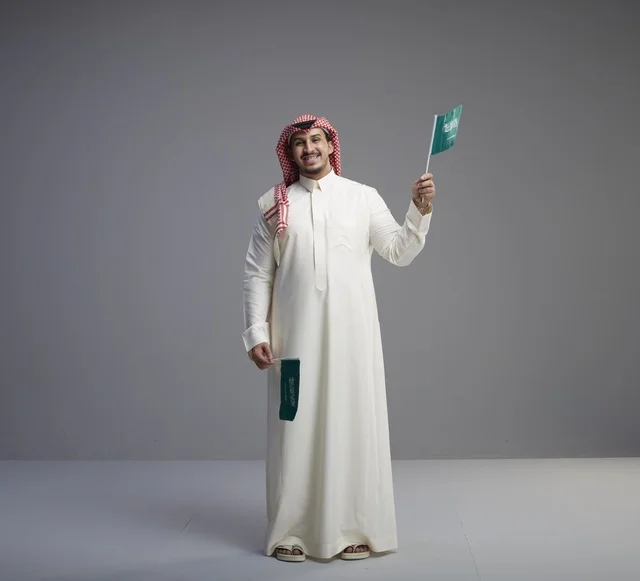 رجل سعودي يحمل الأعلام الوطنية في الاستوديو