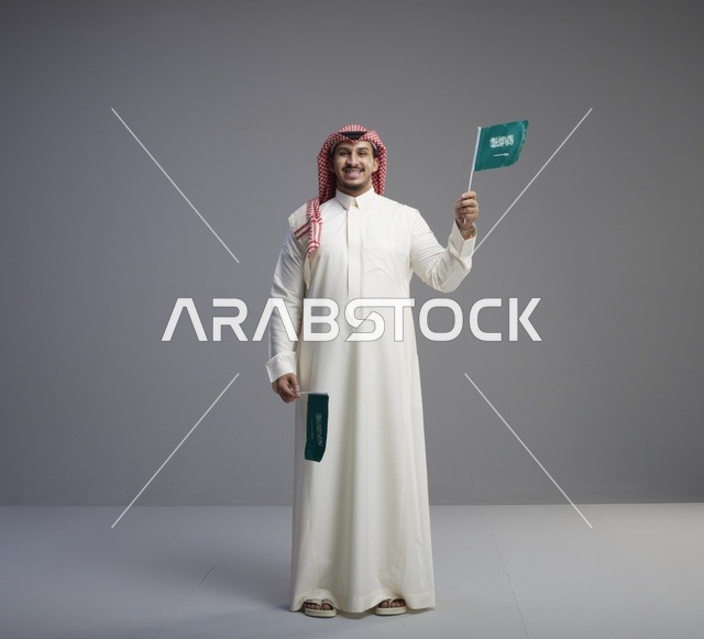 رجل سعودي يحمل الأعلام الوطنية بالزي التقليدي