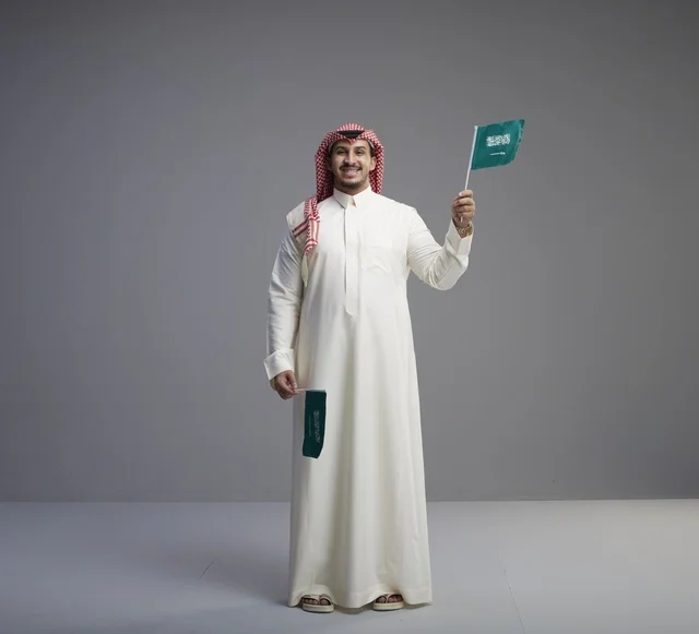 رجل سعودي يحمل الأعلام الوطنية بالزي التقليدي