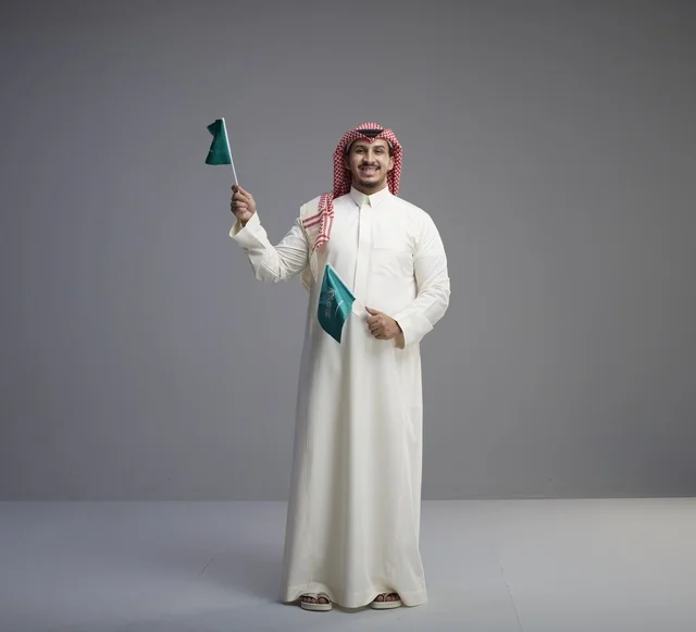 Saudi Man Holding Saudi Arabian National Flags in Studio