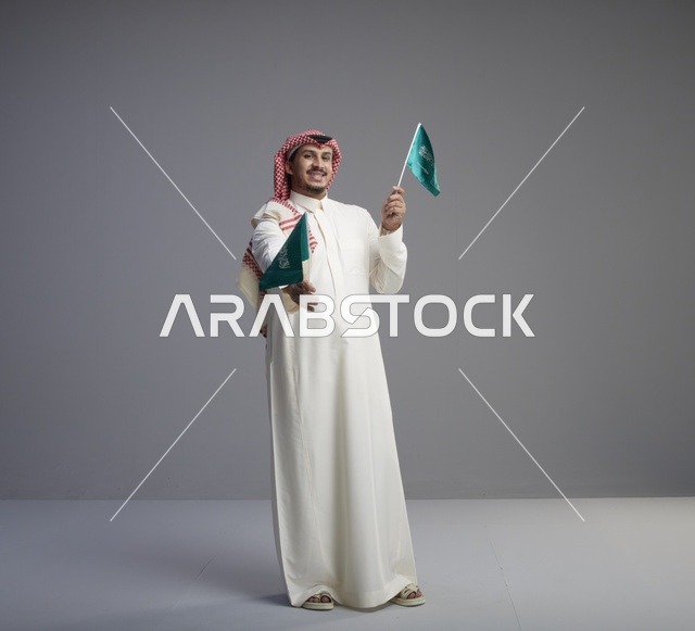 رجل سعودي يحمل الأعلام السعودية في استوديو