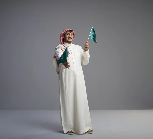 رجل سعودي يحمل الأعلام السعودية في استوديو
