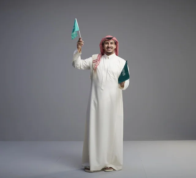 Saudi Man Holding Saudi Arabian Flags in Studio