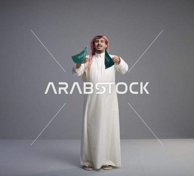 رجل سعودي يحمل الأعلام الوطنية السعودية في استوديو