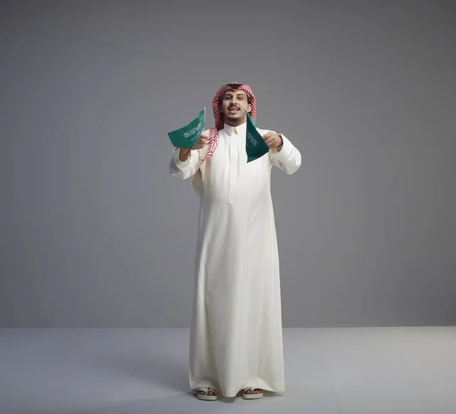 رجل سعودي يحمل الأعلام الوطنية السعودية في استوديو