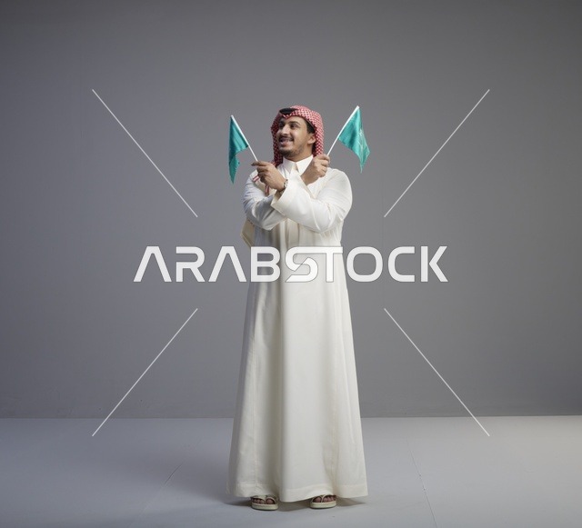 رجل سعودي يحمل أعلام المملكة العربية السعودية
