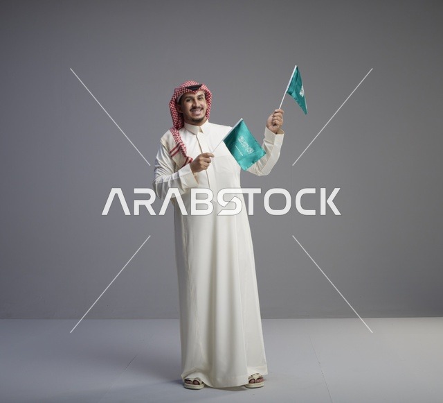 رجل سعودي يحمل أعلام المملكة العربية السعودية