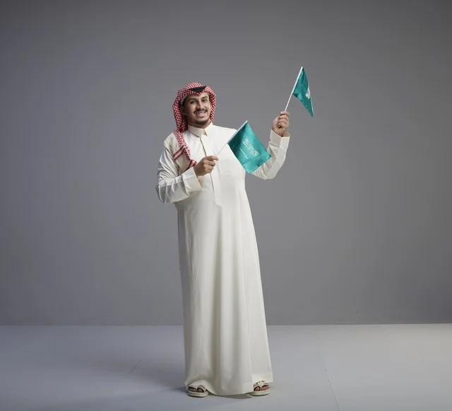 رجل سعودي يحمل أعلام المملكة العربية السعودية