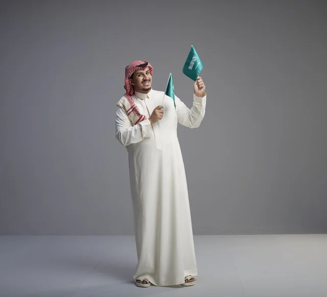 رجل سعودي يحمل العلم السعودي في الاستوديو