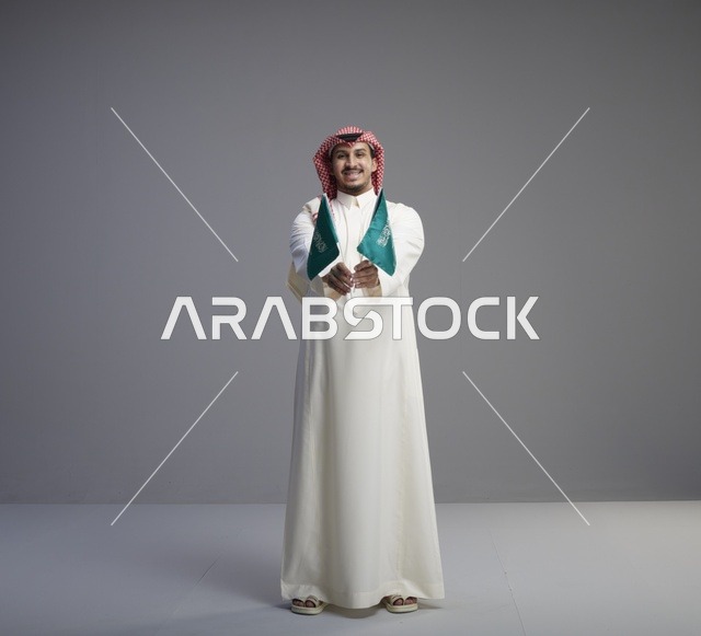رجل سعودي يحمل أعلام السعودية في الاستوديو
