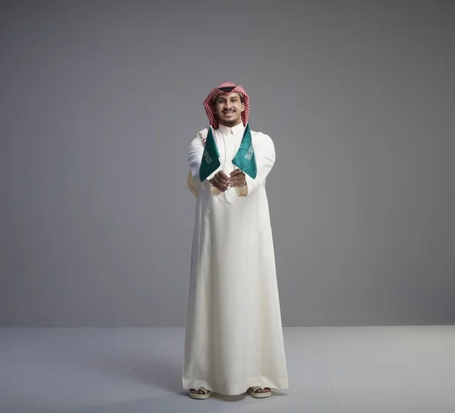 رجل سعودي يحمل أعلام السعودية في الاستوديو