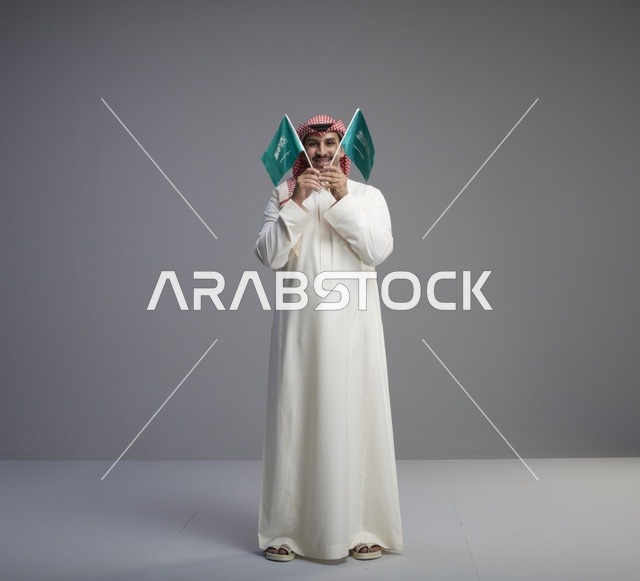 رجل سعودي يحمل علم السعودية في الاستوديو