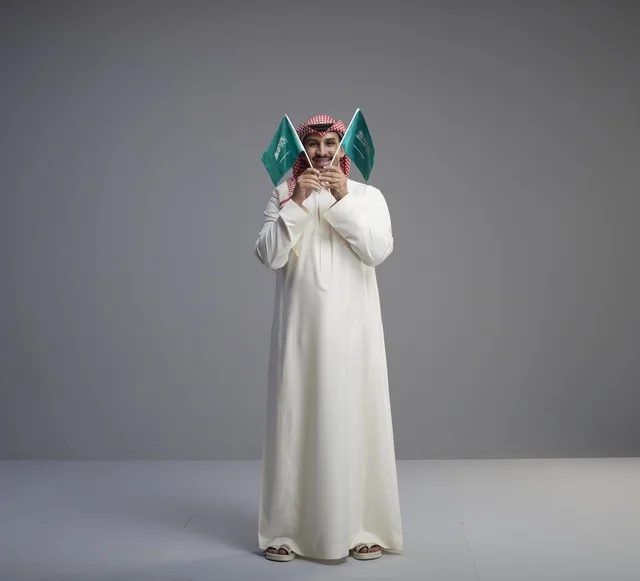 رجل سعودي يحمل علم السعودية في الاستوديو