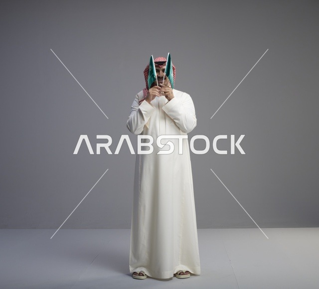 رجل سعودي يحمل علم المملكة في الاستوديو