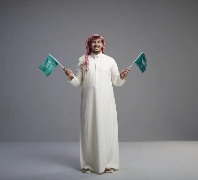 Saudi Man Holding Two Saudi Flags in Studio