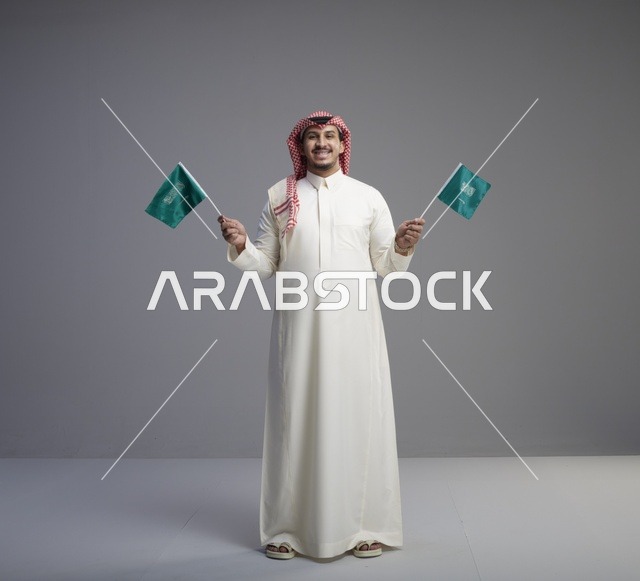 رجل سعودي يحمل أعلام المملكة العربية السعودية في استوديو