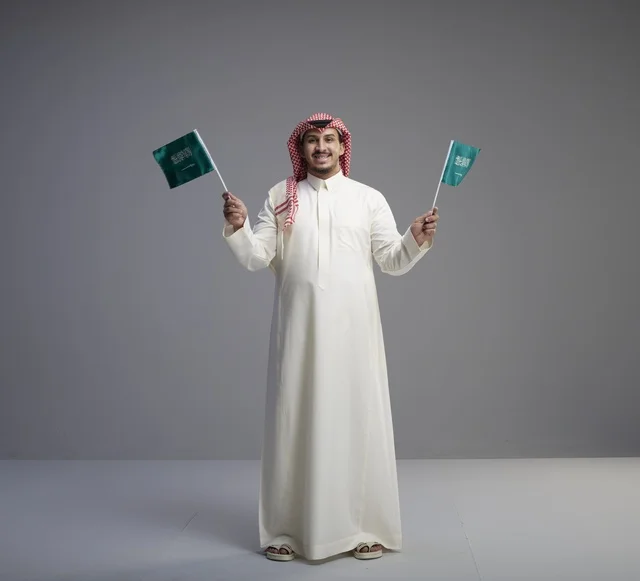 Saudi Man Holding Saudi Arabia National Flags in Studio