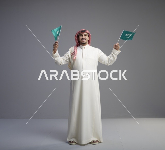 رجل سعودي يحمل الأعلام الوطنية في الاستوديو