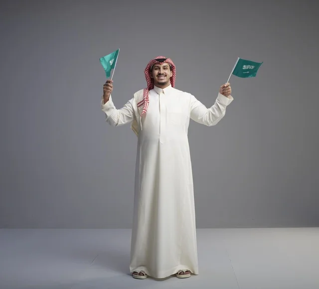 رجل سعودي يحمل الأعلام الوطنية في الاستوديو