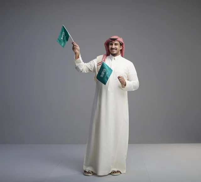 Saudi Man Holding Flags on Grey Studio Background