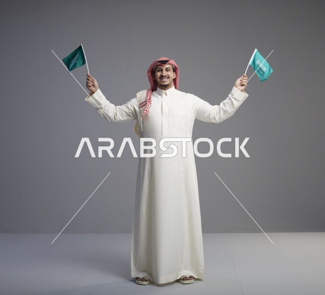 رجل سعودي يحمل الأعلام الوطنية بالزي التقليدي