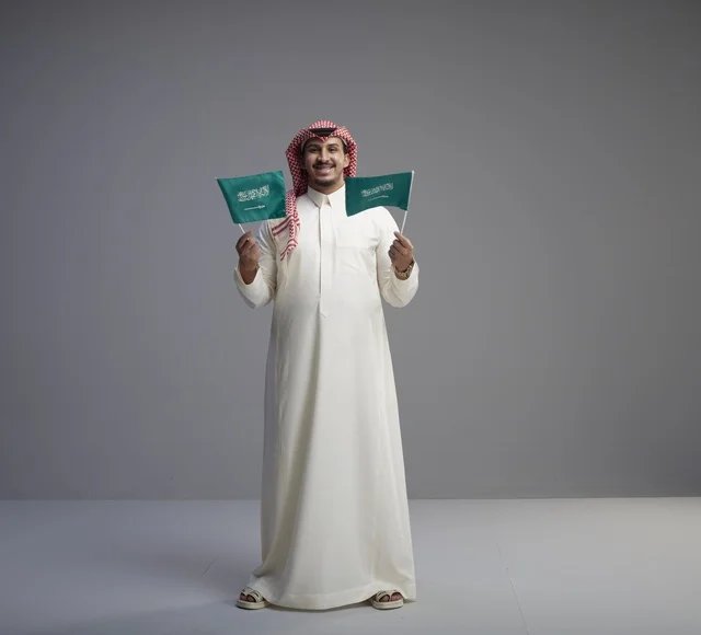 Saudi Man Holding National Flags on Grey Background