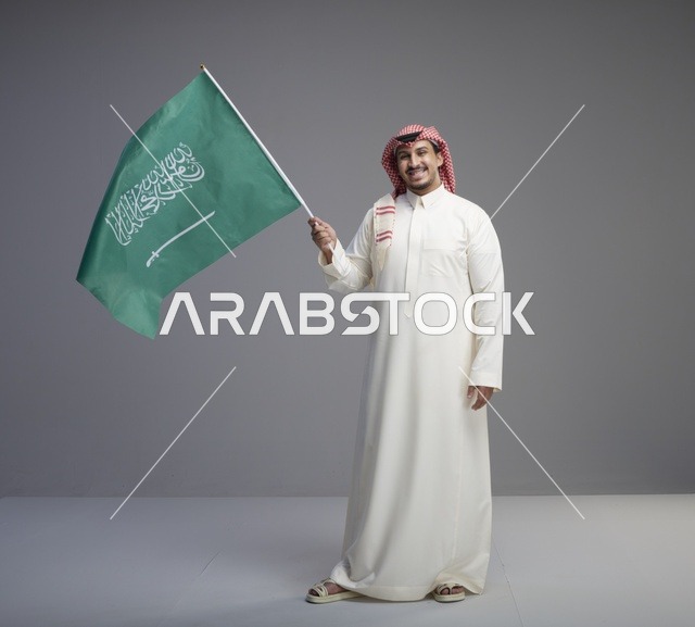 رجل سعودي يحمل العلم السعودي في الاستوديو