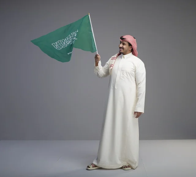 رجل سعودي يحمل العلم الوطني في استوديو تصوير احترافي