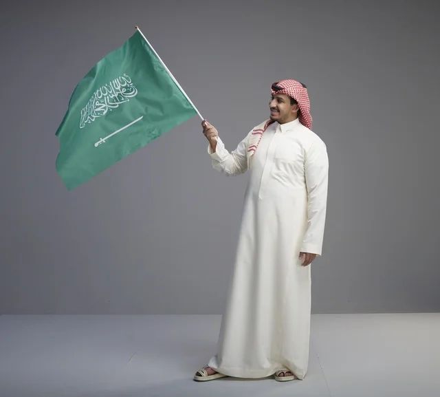Saudi Man in Traditional Dress Holding Saudi Arabia Flag