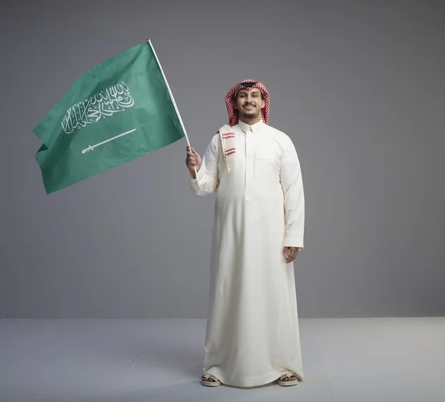 Saudi Man Holding Saudi National Flag in Studio Portrait