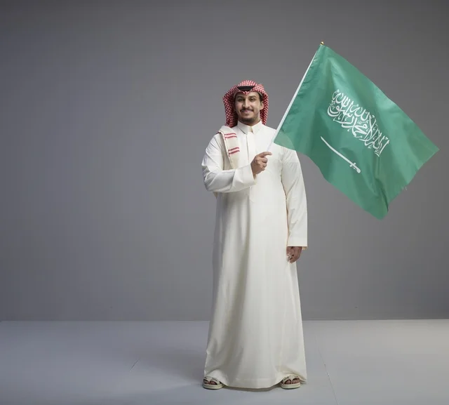 رجل سعودي يحمل العلم الوطني السعودي في الاستوديو