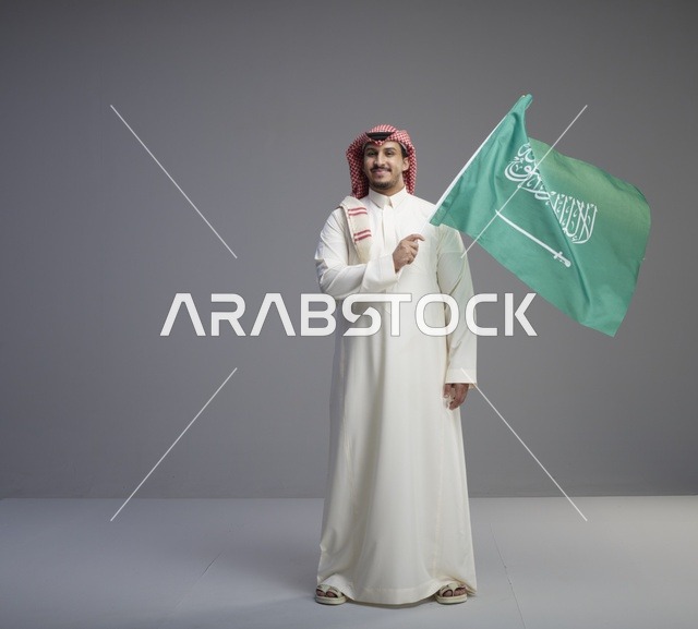 رجل سعودي يحمل علم السعودية في الاستوديو