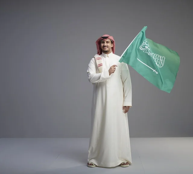Saudi Man Holding Saudi Arabian Flag in Studio