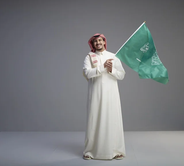 رجل سعودي يحمل العلم السعودي في استوديو