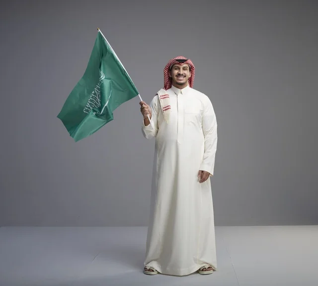 رجل سعودي يحمل العلم السعودي في الاستوديو