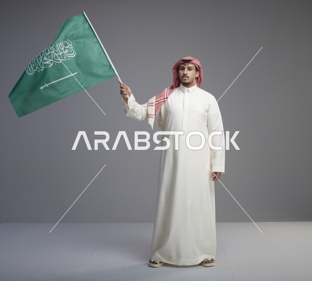 رجل سعودي يرفع العلم السعودي في الاستوديو