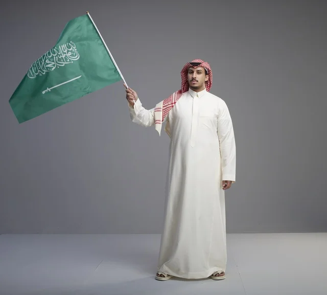 رجل سعودي يرفع العلم السعودي في الاستوديو