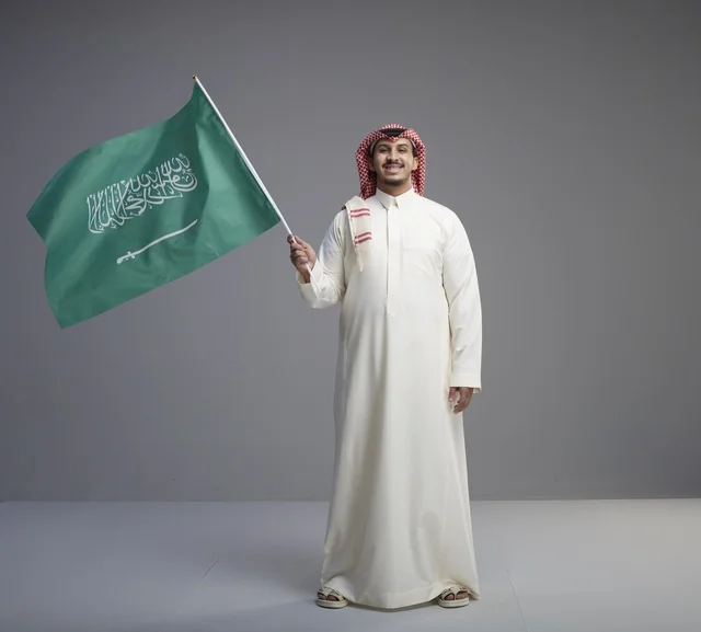 رجل سعودي يمسك بالعلم الوطني في استوديو تصوير