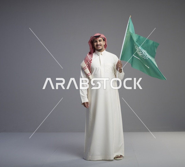 رجل سعودي يحمل علم المملكة العربية السعودية في استوديو