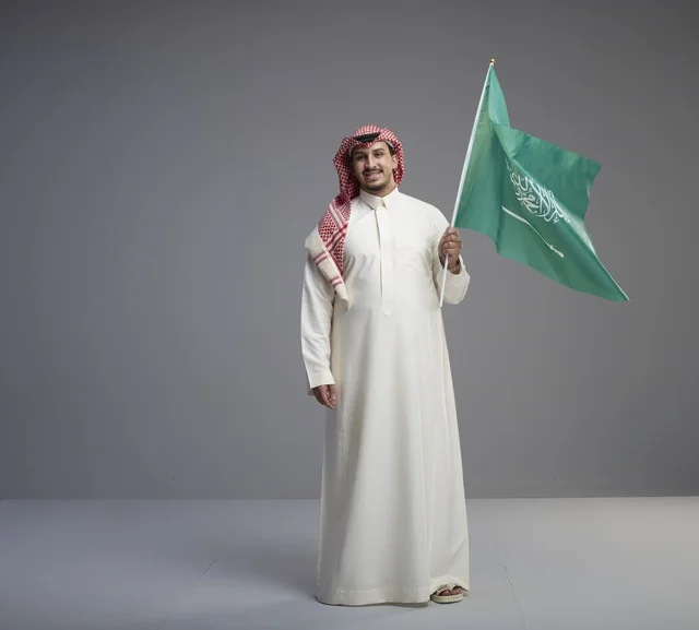 رجل سعودي يحمل علم المملكة العربية السعودية في استوديو